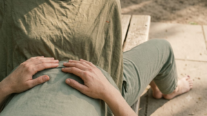 A person lying on their back with knees bent, resting still, photographed in soft natural light.