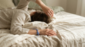 A photograph of a person reaching one arm overhead and leaning to the opposite side, face out of frame.