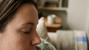 In profile in a deep armchair, a person breathes in slowly through their nose with eyes closed.