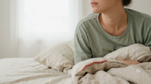 A photograph cropped at the chin showing the neck and shoulders of a person lying on their side with their head on a pillow.
