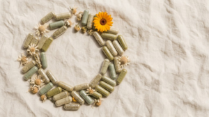 A still life photograph of loose herbal supplement capsules scattered with dried chamomile flowers on a plain pale surface.