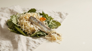 Sauerkraut, an oily fish fillet and leafy greens arranged on a plain linen surface.